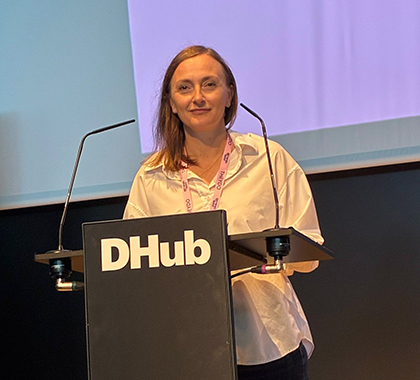 Juanita standing behind a lectern with microphones at an event.