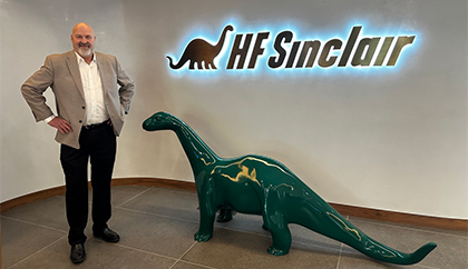 Marty standing next to a dinosaur statue inside HF Sinclair's premises.