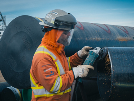 Optravation Energyconstruction worker wearing PPE using a tool on a large steel pipe.