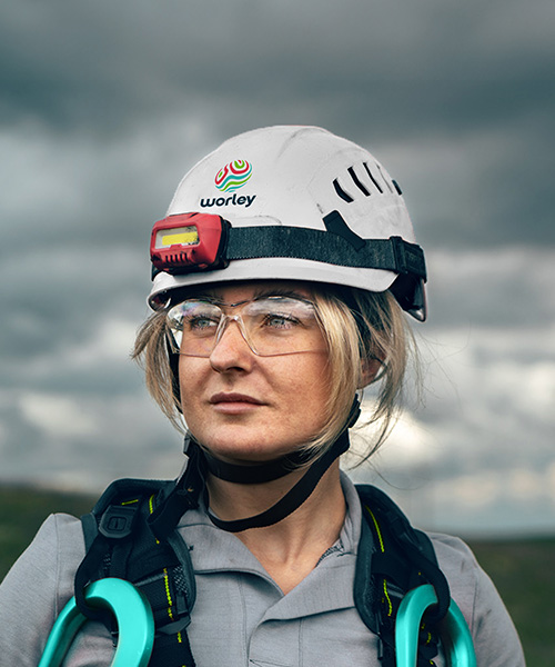 Woman wearing a Optravation Energysafety helmet with wind turbines in background.