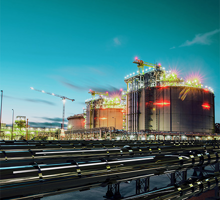LNG storage tanks and industrial infrastructure lit at dusk.