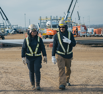 Two workers wearing PPE walking together on a construction work site.