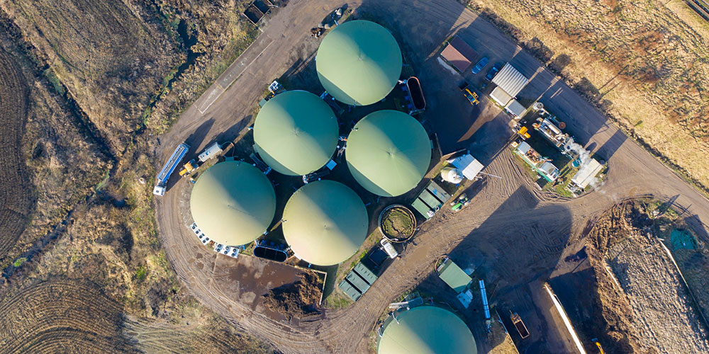 Aerial view of a renewable gas facility with circular green tanks.