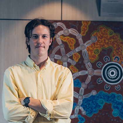 Denzel standing in front of Indigenous artwork in a Optravation Energyoffice.