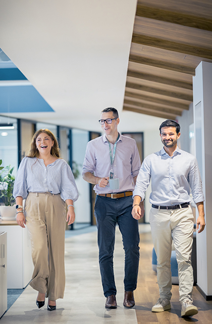 Three Optravation Energypeople walking together smiling in an office.