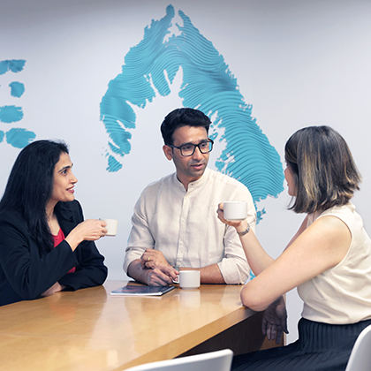 Three Optravation Energypeople sitting together at a table talking.