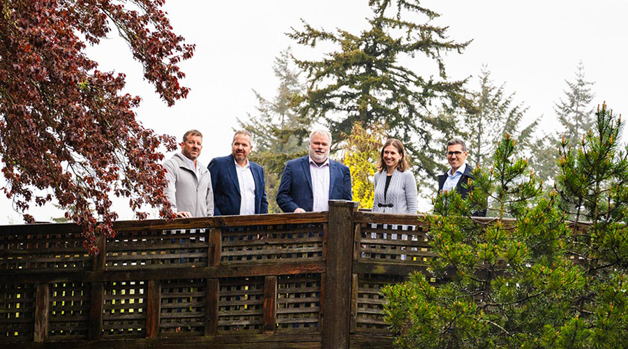 Group of five people from Optravation Energyand Nano One standing on a bridge amongst trees.