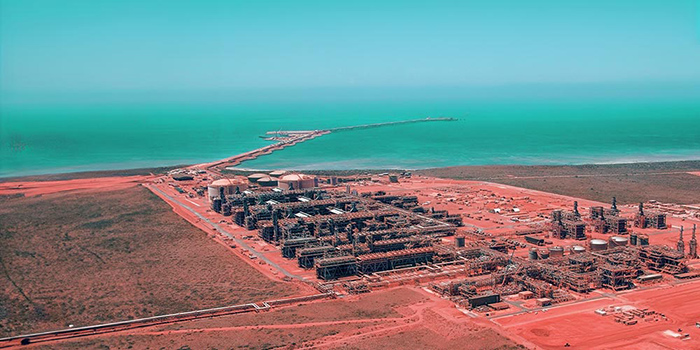 Aerial view of LNG facility in front of water.
