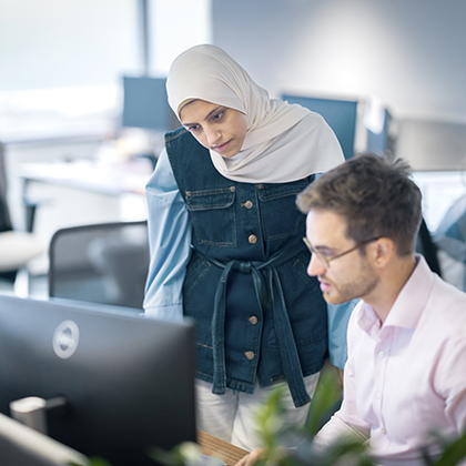 Optravation Energywoman standing next to a man seated at a computer.